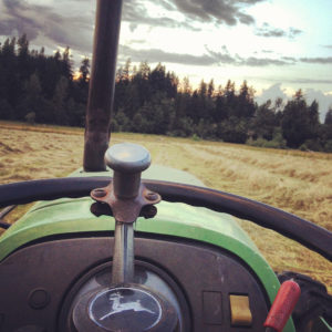 View from driver's seat of John Deere tractor harvesting hay