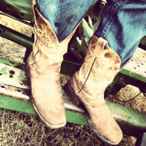 Rugged western boots on tractor step