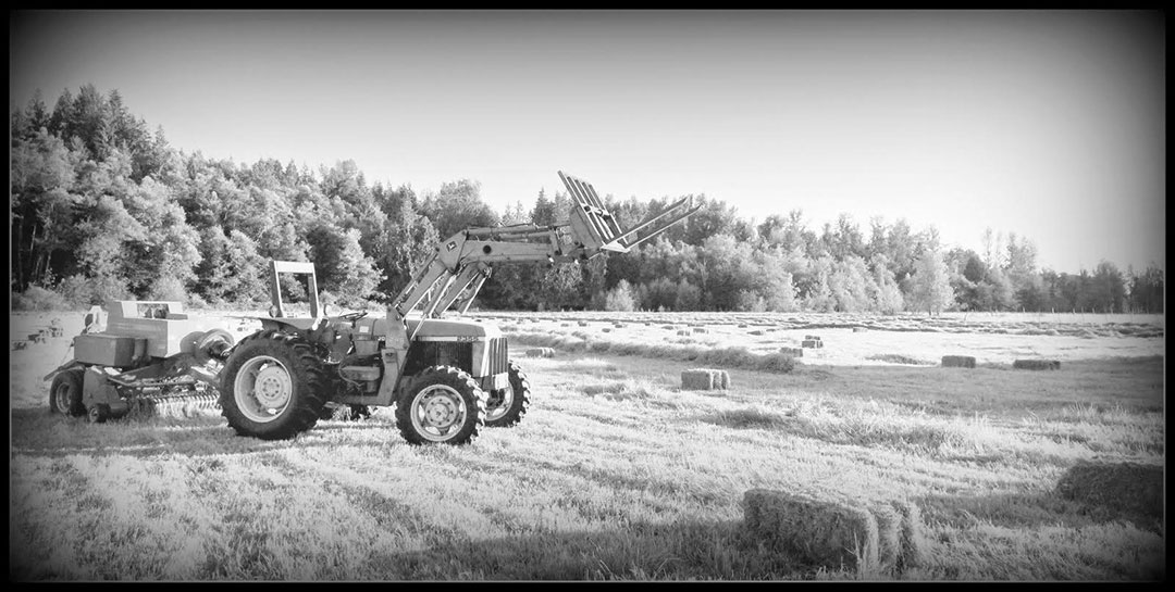John Deere tractor with baler in a hay field